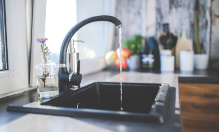 Water faucet turned on filling a glass with drinking water