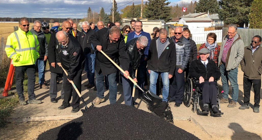 Individuals shovel asphalt on the last section of rotary trail