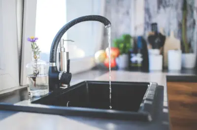 Water faucet turned on filling a glass with drinking water